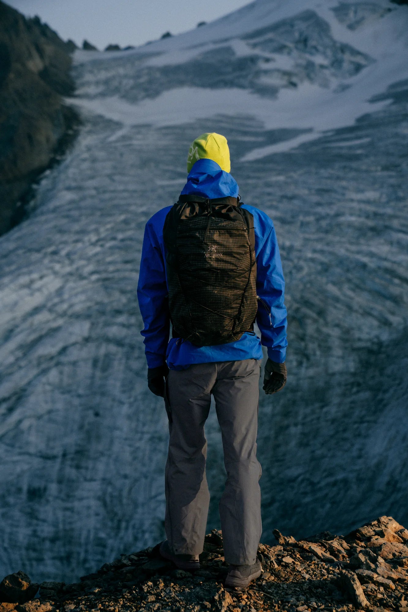 Person in blue jacket and yellow beanie standing on a glacier