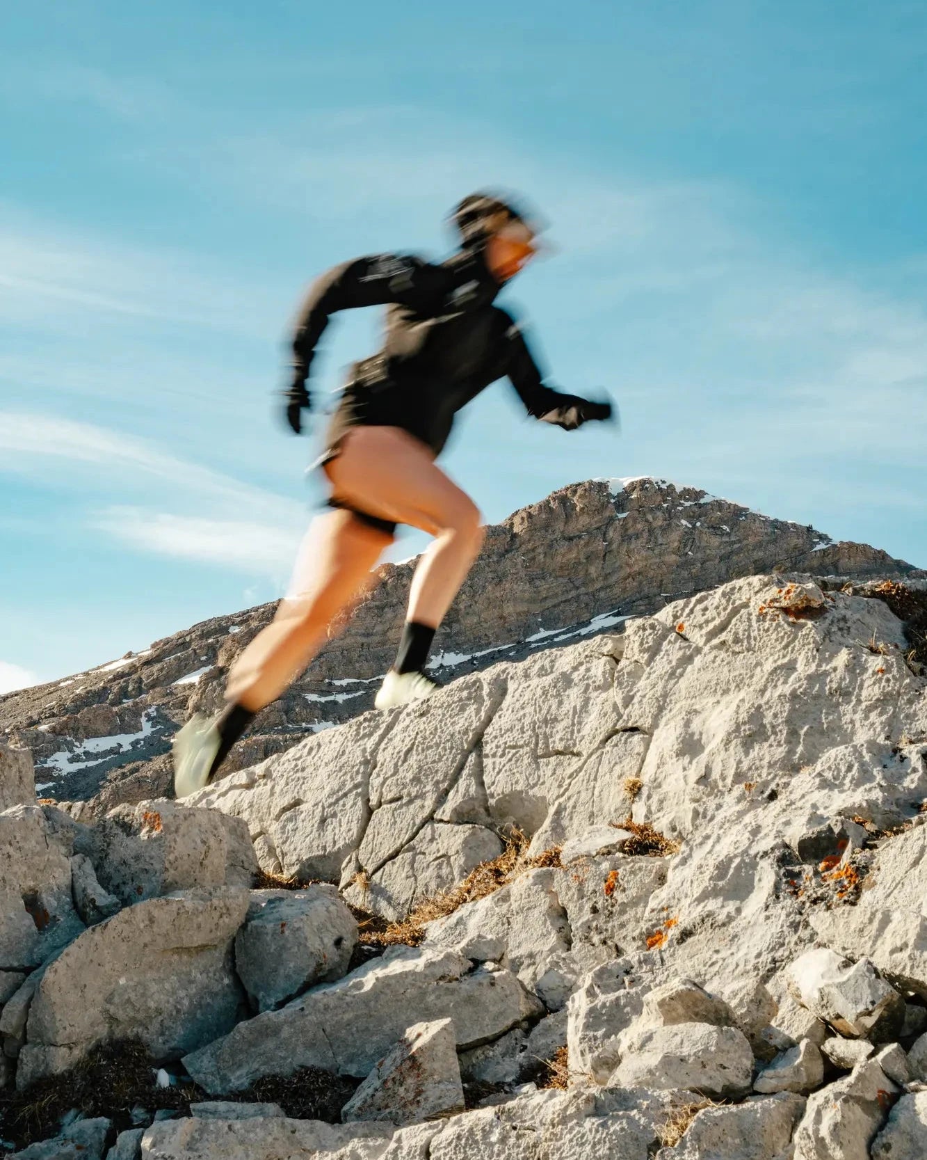 Person running on rocky terrain with a mountainous landscape in the background
