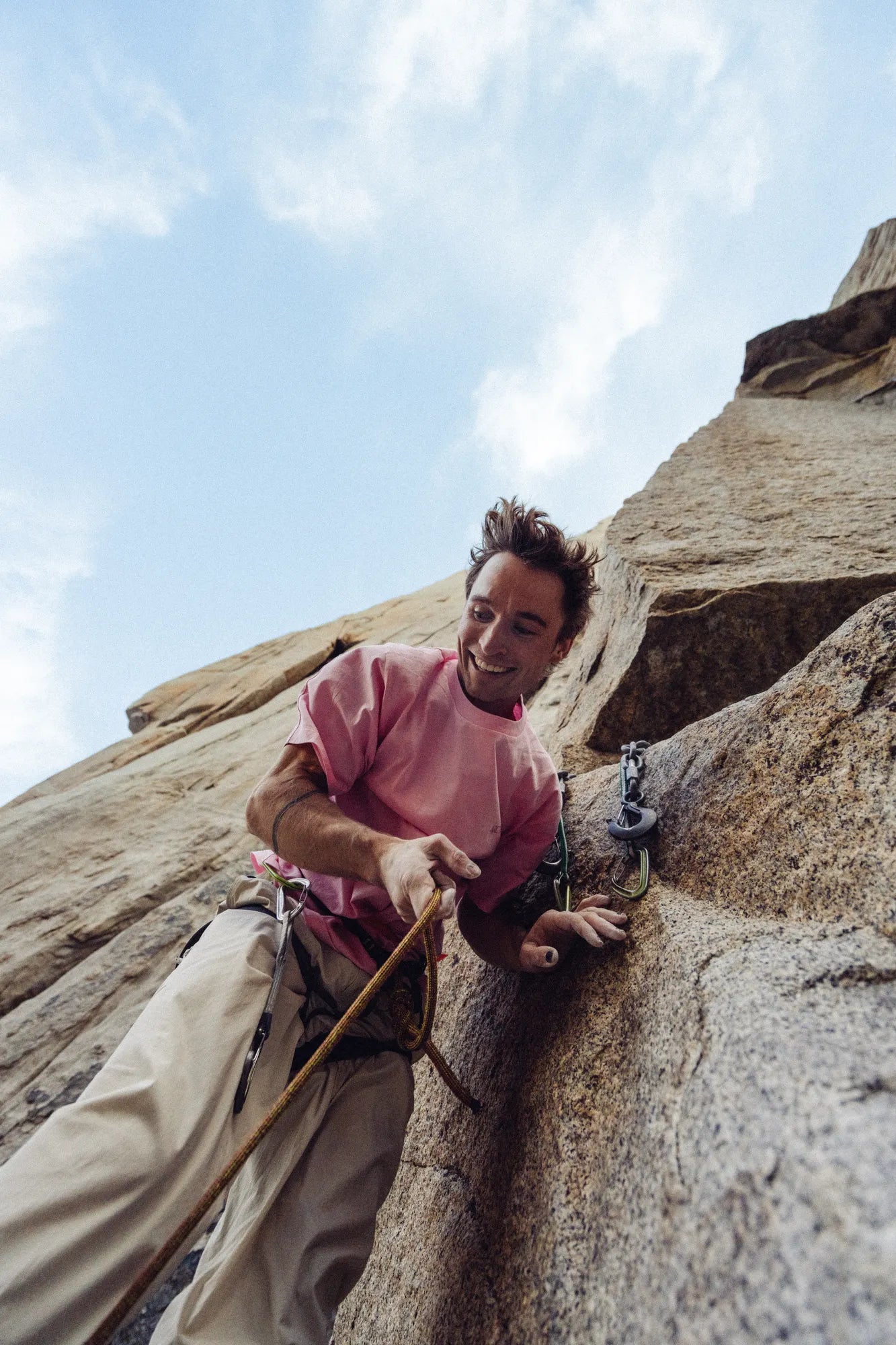 Person rock climbing a cliff with a clear sky above